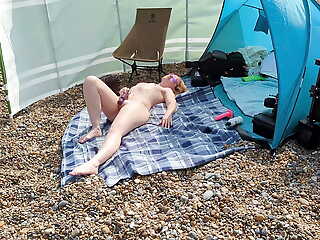 A young blonde wife is bare-ass and masturbating on a British public beach